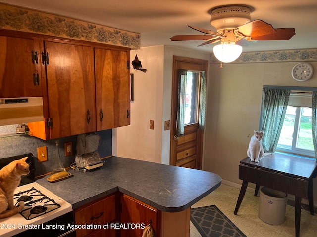 kitchen featuring white range with gas cooktop, kitchen peninsula, tasteful backsplash, and ceiling fan