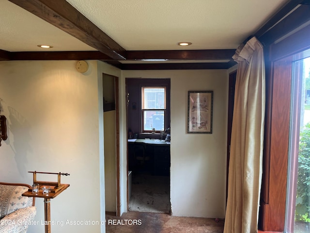 hall featuring beamed ceiling and a textured ceiling