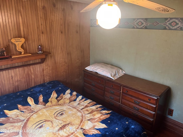 bedroom with wooden walls and ceiling fan