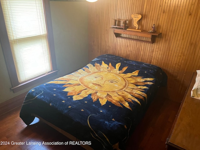 bedroom with dark wood-type flooring and wood walls