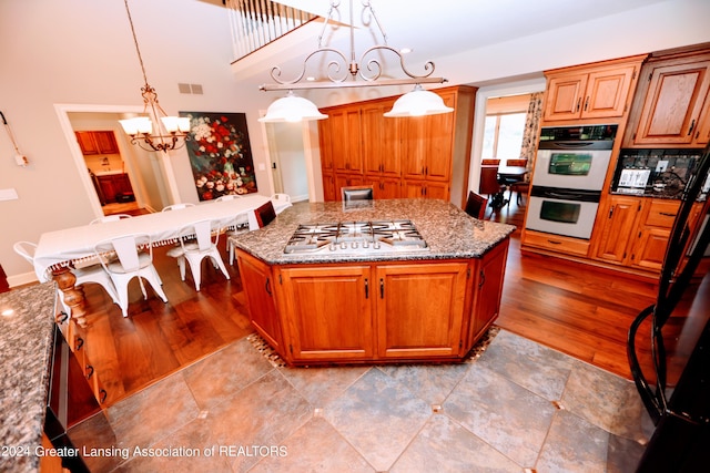 kitchen featuring pendant lighting, stainless steel gas stovetop, a center island, and light stone counters