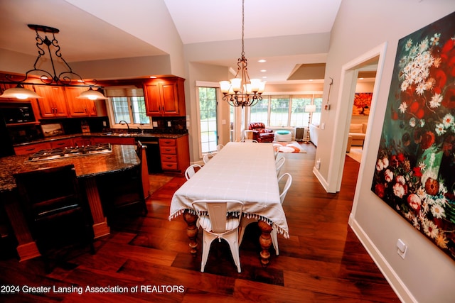 dining area featuring sink, dark wood-type flooring, vaulted ceiling, and an inviting chandelier