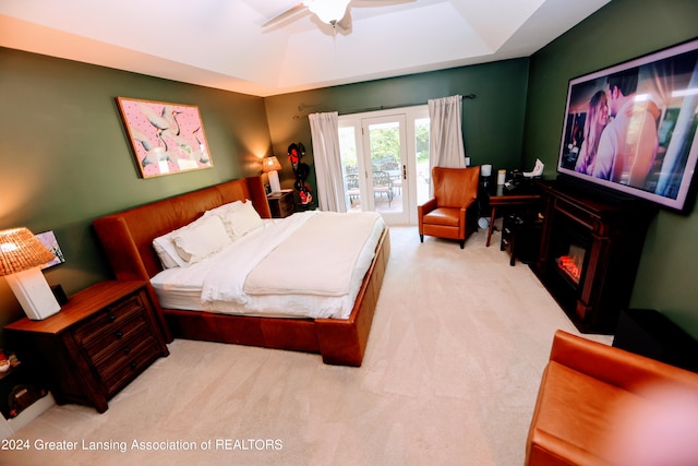 bedroom with access to outside, a raised ceiling, ceiling fan, and light colored carpet