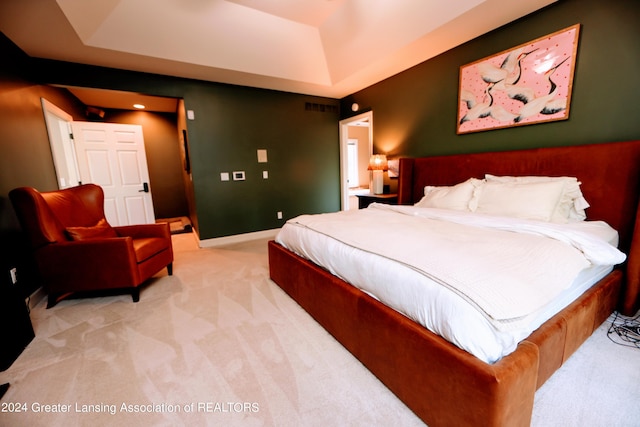 bedroom featuring light colored carpet and a tray ceiling