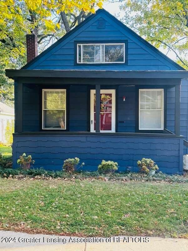 bungalow-style home featuring covered porch and a front lawn