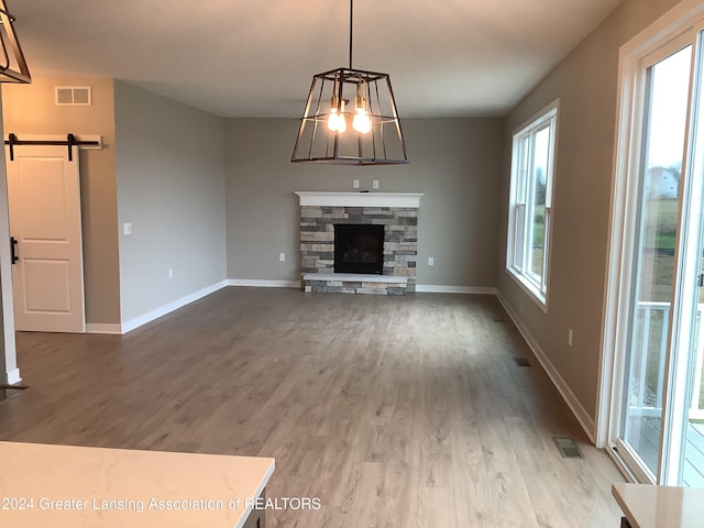 unfurnished living room featuring hardwood / wood-style floors, a barn door, and a fireplace