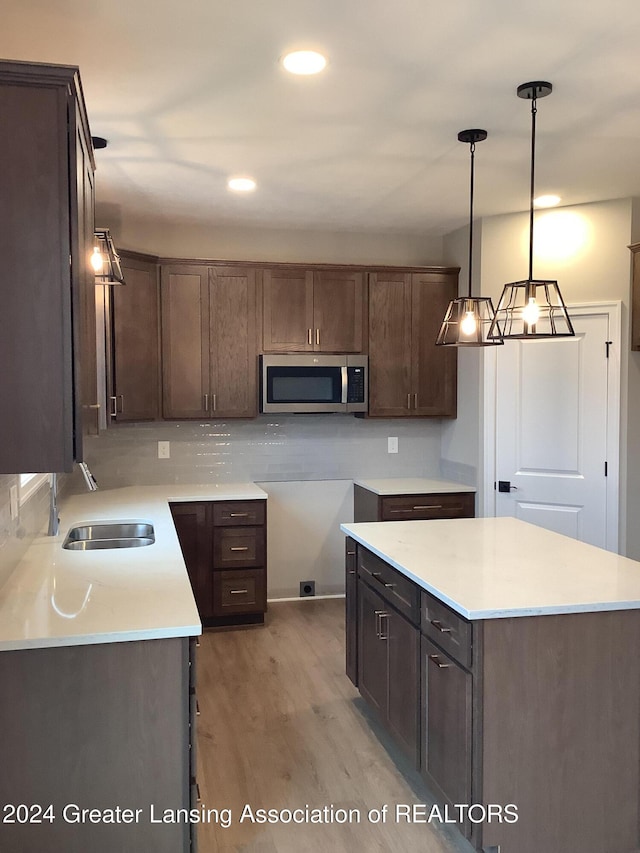 kitchen featuring dark brown cabinets, decorative light fixtures, light hardwood / wood-style flooring, and sink