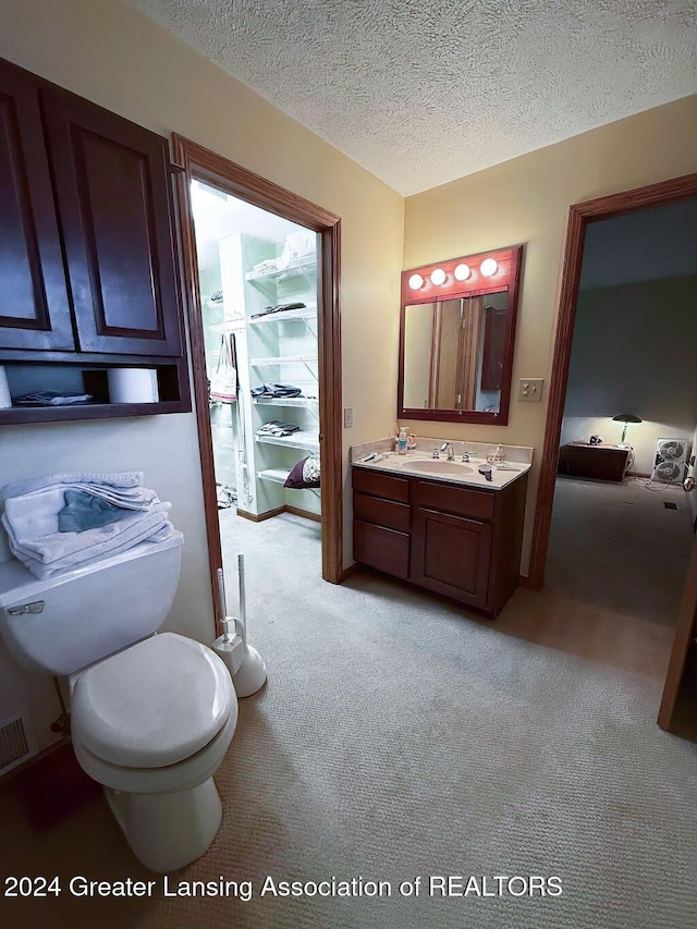 bathroom with vanity, toilet, and a textured ceiling