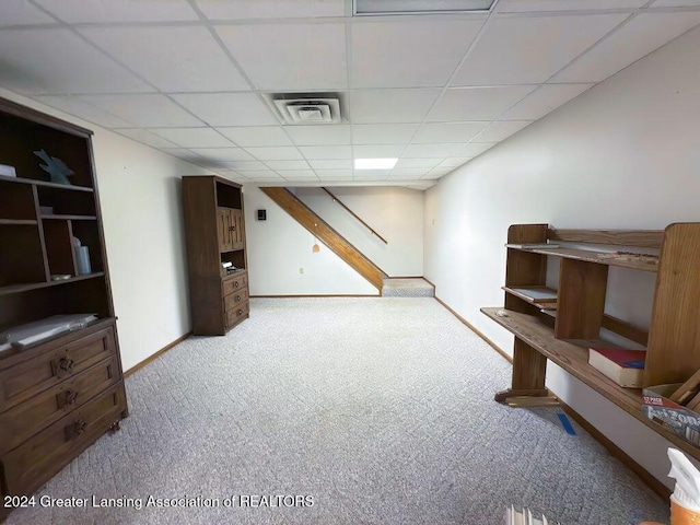 basement featuring light colored carpet and a paneled ceiling