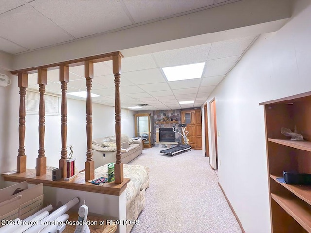 basement with carpet floors, a wall unit AC, a drop ceiling, and a fireplace