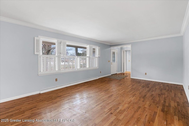 spare room featuring crown molding, baseboards, baseboard heating, and wood finished floors