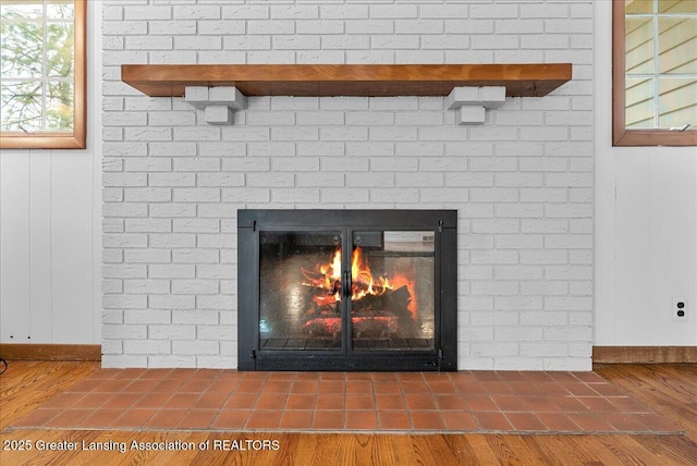 details featuring a brick fireplace, baseboards, and wood finished floors