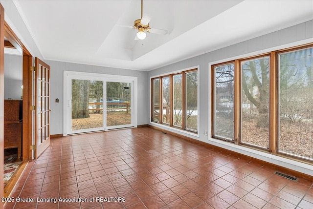 unfurnished sunroom featuring ceiling fan, a tray ceiling, and visible vents