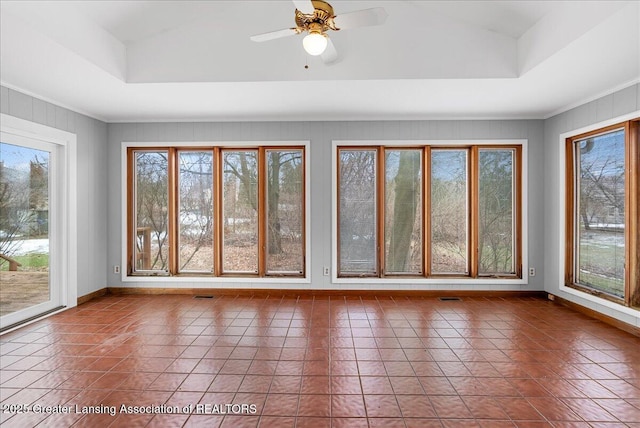 unfurnished sunroom featuring lofted ceiling, visible vents, a raised ceiling, and a ceiling fan