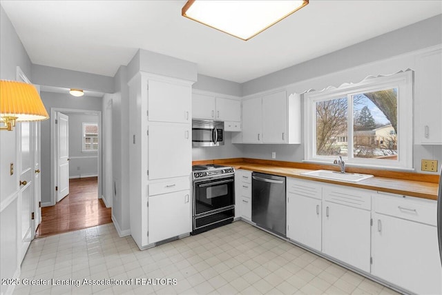 kitchen featuring light countertops, appliances with stainless steel finishes, a sink, and white cabinets