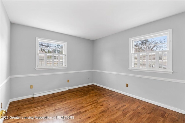 spare room featuring baseboards, baseboard heating, and wood finished floors