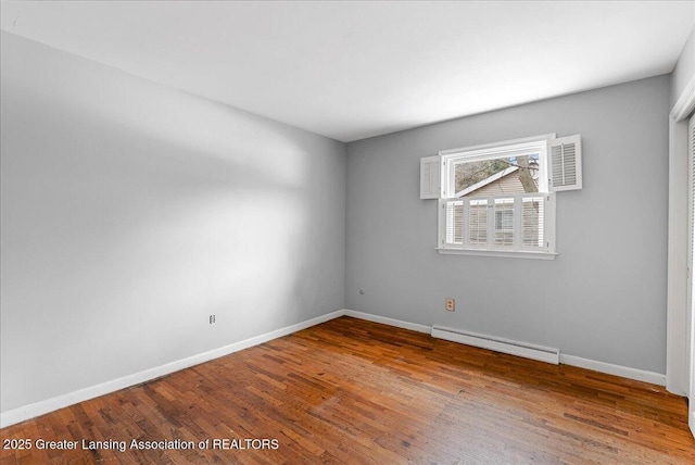 unfurnished room with a baseboard radiator, baseboards, and wood finished floors