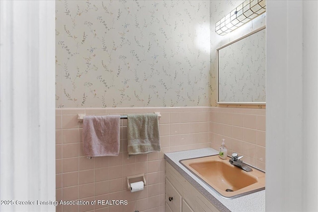 bathroom featuring wallpapered walls, a wainscoted wall, and vanity