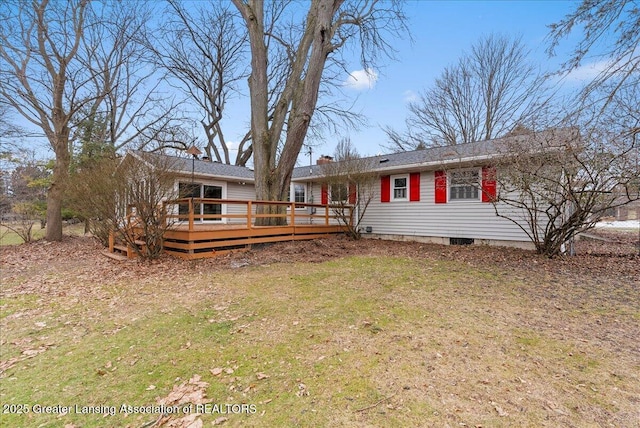 rear view of property featuring a yard, a chimney, and a wooden deck