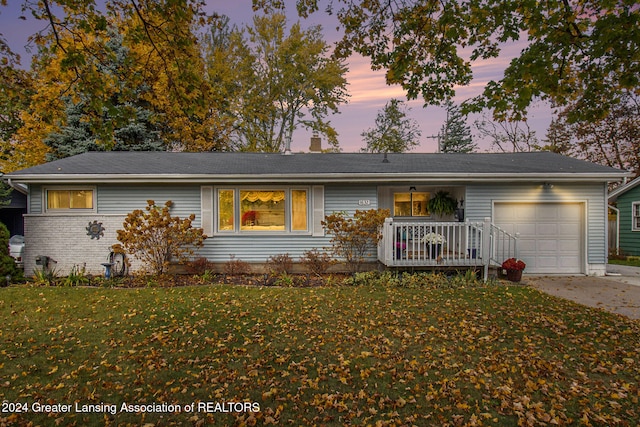 single story home featuring a garage and a lawn