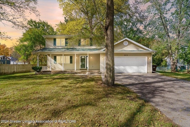 view of front facade with covered porch, a garage, and a lawn