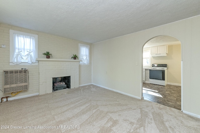 unfurnished living room with light carpet, a healthy amount of sunlight, heating unit, and a brick fireplace