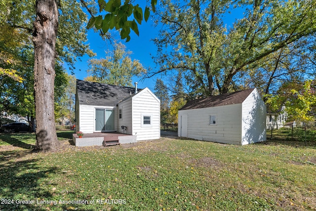 back of property featuring a storage unit and a lawn