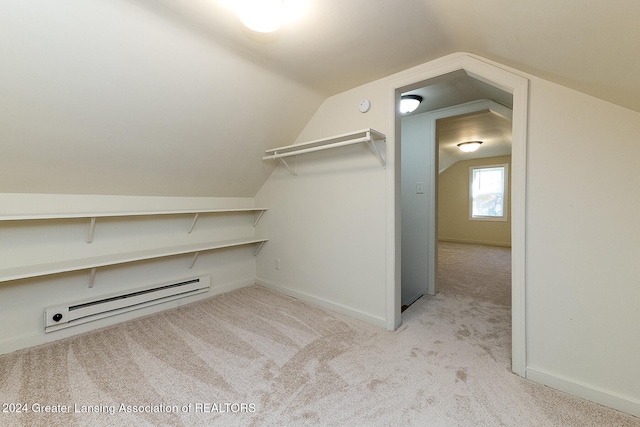 walk in closet with light colored carpet, a baseboard radiator, and vaulted ceiling