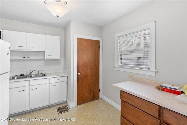 kitchen with sink, white cabinets, white refrigerator, and light tile patterned floors