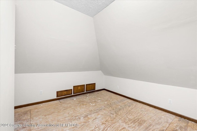 additional living space with a textured ceiling and vaulted ceiling