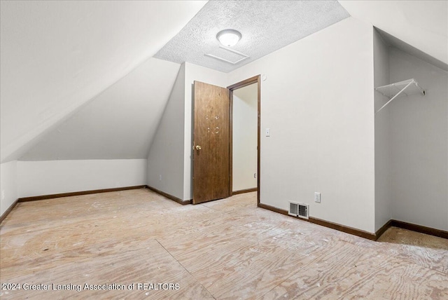 additional living space featuring lofted ceiling and a textured ceiling