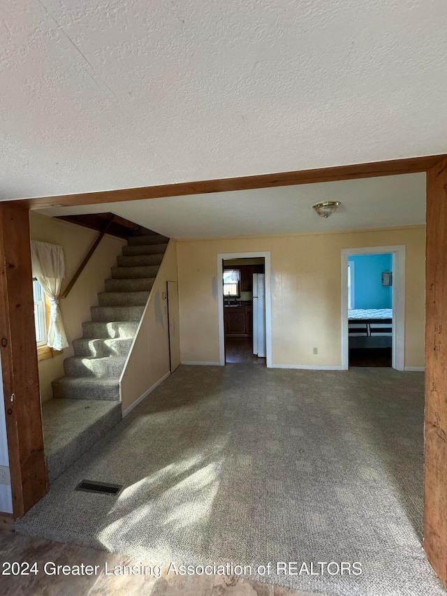 unfurnished living room with carpet and a textured ceiling