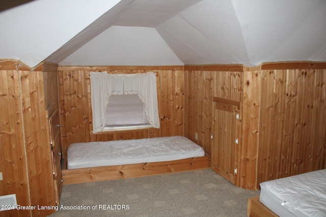 unfurnished bedroom featuring lofted ceiling, wooden walls, and carpet floors