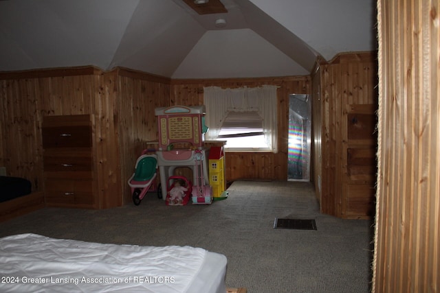 carpeted bedroom with wooden walls and vaulted ceiling