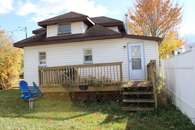 rear view of house featuring a deck, a yard, roof with shingles, and fence
