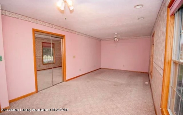 carpeted spare room featuring ceiling fan