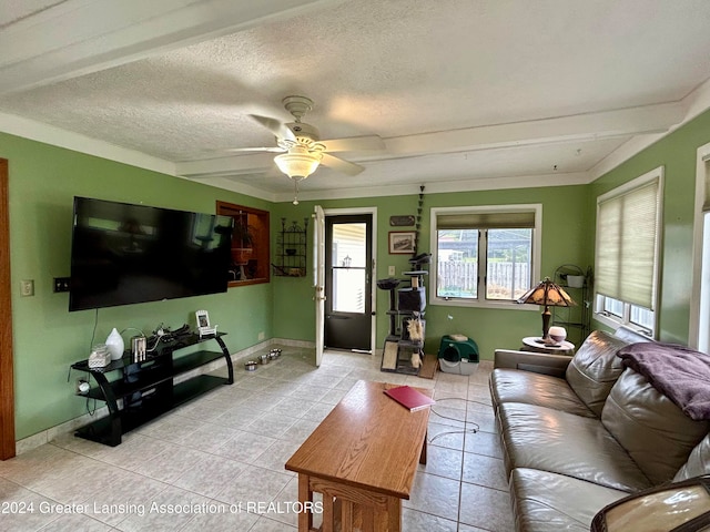 living room with light tile patterned flooring, a textured ceiling, ceiling fan, beamed ceiling, and crown molding