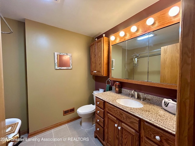 bathroom with vanity, a shower, toilet, and tile patterned flooring