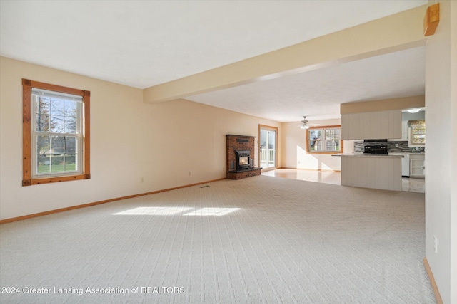 unfurnished living room with light carpet, beamed ceiling, plenty of natural light, and ceiling fan