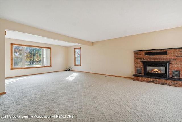 unfurnished living room with beam ceiling, carpet flooring, and a brick fireplace