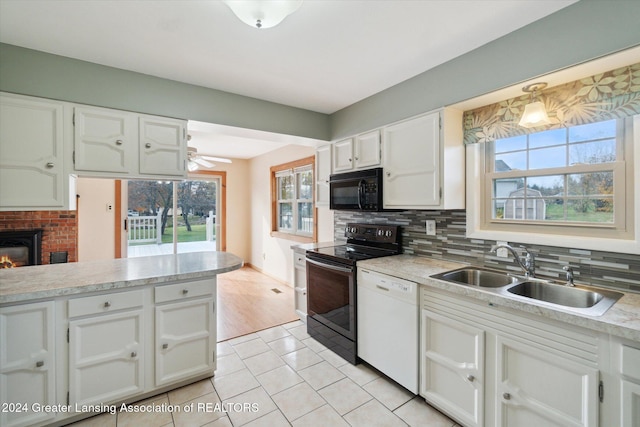 kitchen with black appliances, sink, a fireplace, and white cabinets