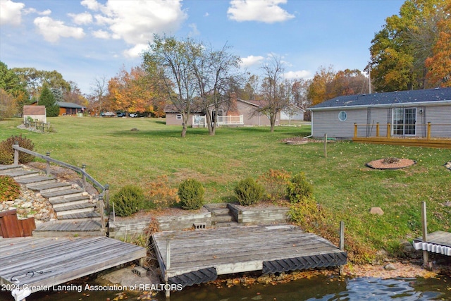 view of yard featuring a water view, a boat dock, and an outdoor fire pit