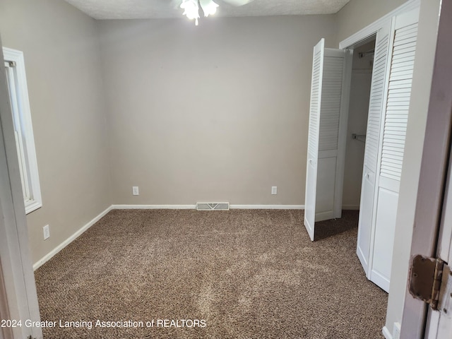 unfurnished bedroom featuring a closet, a textured ceiling, and dark colored carpet