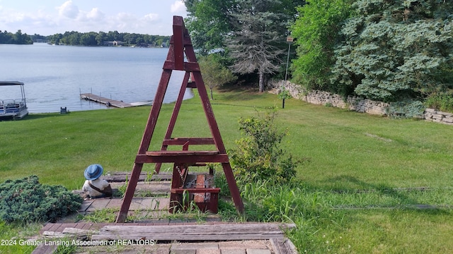 view of play area featuring a water view, a dock, and a yard