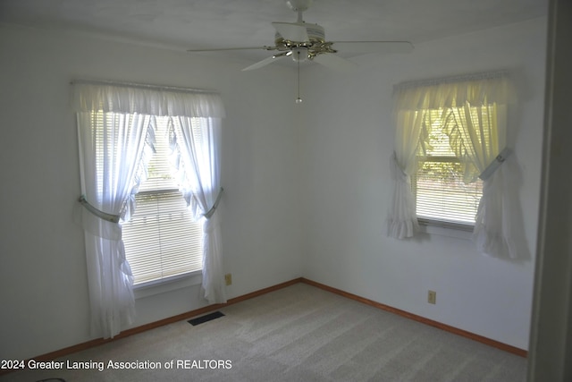 carpeted empty room with ceiling fan and plenty of natural light