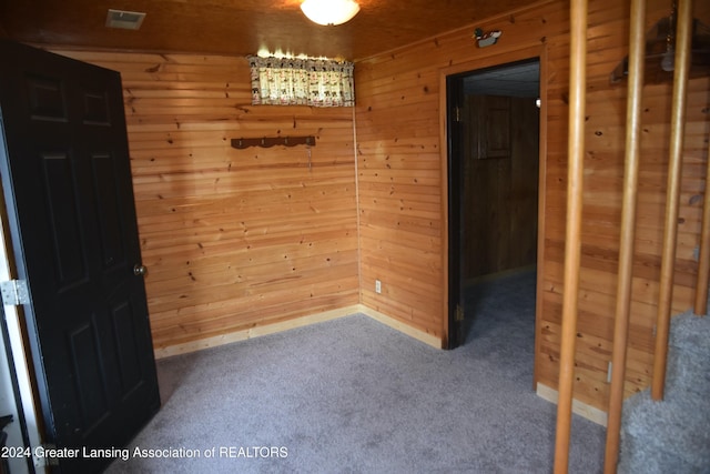 carpeted spare room with wooden walls