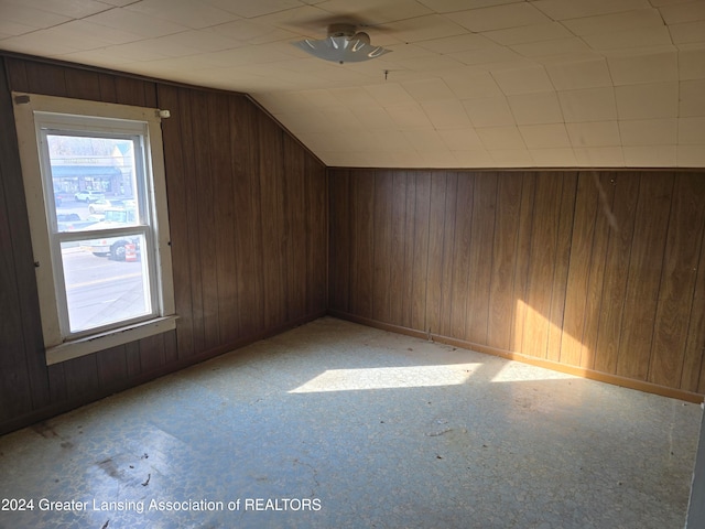 additional living space featuring lofted ceiling and wooden walls