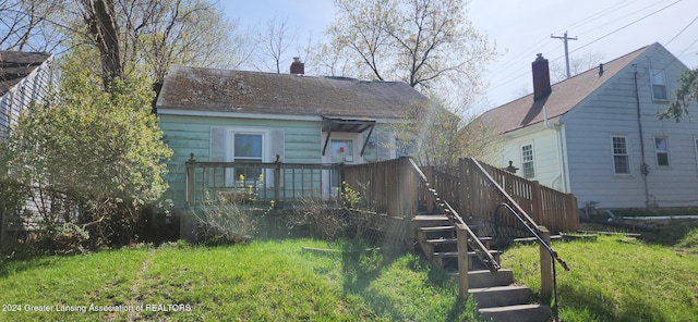 rear view of house featuring a wooden deck and a yard