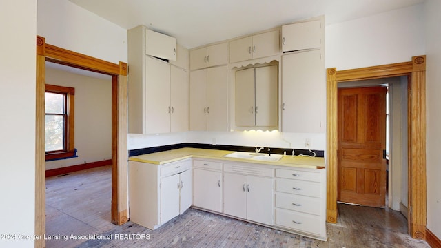 kitchen with white cabinetry, sink, and light hardwood / wood-style floors