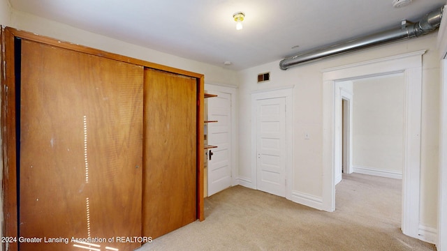 unfurnished bedroom featuring light colored carpet and a closet